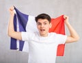 Energized,active male spectator holds national flag of France in hands and chants popular slogan
