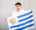 Energized,active male spectator holds national flag of Uruguay in hands and chants popular slogan.