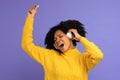 Energized biracial woman sing along, wears wireless headphones, has good mood, isolated on violet background. Happy dark skinned Royalty Free Stock Photo