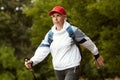 Active sportive elderly woman practicing in Nordic walking with sticks in public park, outdoors. Autumn sports, healthy