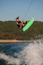 energy athletic guy holding a rope and jumping in the air with bright wakeboard Royalty Free Stock Photo