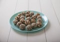 Energy balls of dried fruits and nuts sprinkled with sesame and granola lie on a blue porcelain plate on a white wooden table Royalty Free Stock Photo