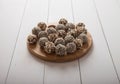 Energy balls made from dates and dried fruits with peanut and granola lie on a wooden board on a white table. Healthly food