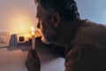 Man in complete darkness holding a candle to investigate thermostat during a power outage. Blackout concept Royalty Free Stock Photo