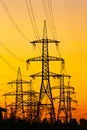 Energy Distribution Network - Electricity Pylons against Orange and Yellow Sunset. Selective focus. Royalty Free Stock Photo