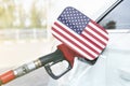 Flag of USA on the car`s fuel filler flap with gas pump nozzle in the tank Royalty Free Stock Photo