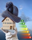 Energy efficiency label for house / heating and money savings - model of a house with cap in a hand in gloves Royalty Free Stock Photo