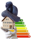 Energy efficiency label for house / heating and money savings - model of a house with cap in a hand in gloves Royalty Free Stock Photo