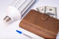 Energy efficiency and modern solutions for reducing electricity cost, led lamp, notebook and dollar banknotes as a concept of Royalty Free Stock Photo