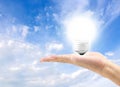 Energy efficient bulb in hand with blue sky in background Royalty Free Stock Photo