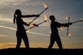 Energy entertainment. Sexy couple manipulate flaming batons. Dark shades on idyllic evening sky. Fire performance