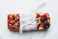 Energy granola bar with almonds, raisins and dried berries on white marble background. Healthy snack concept Royalty Free Stock Photo