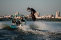 energy wakeboarder moving fast behind boat holding rope and masterfully jumping high on splashing river wave. Royalty Free Stock Photo