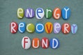 Energy Recovery Fund, economical phrase composed with multi colored stone letters over green sand