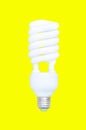 Fluorescent spiral light bulb isolated on yellow background Royalty Free Stock Photo