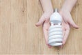 Energy saving concept, Woman hand holding light bulb on wooden background Royalty Free Stock Photo