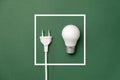 Energy-saving and eco-friendly life. Creative top view flat lay of LED light bulb, electrical plug and white frame with copy space
