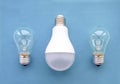 Energy-saving lamp with incandescent lamps in a row on a blue background. The concept of saving energy Royalty Free Stock Photo