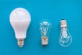 Energy-saving lamp with incandescent lamps in a row on a blue background. The concept of saving energy Royalty Free Stock Photo