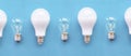 Energy-saving lamps with incandescent lamps in a row on a blue background. The concept of saving energy Royalty Free Stock Photo