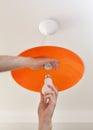 Energy-saving LED light bulb in the human hand, the replacement of the lamp in the ceiling luminaire made of orange ground glass Royalty Free Stock Photo