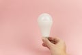 Energy saving LED Light bulb in woman& x27;s hand on pink bacground close up. Concept of saving energy Royalty Free Stock Photo