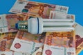 Energy saving light bulb close-up on a background of banknotes Royalty Free Stock Photo