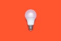 An energy-saving light bulb on an orange background in the center of the image Royalty Free Stock Photo