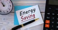 ENERGY SAVING - words on a white sheet on the background of a calculator, alarm clock and pen Royalty Free Stock Photo