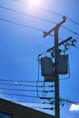 Energy and technology: electrical post by the road with power line cables, transformers against bright blue sky Royalty Free Stock Photo