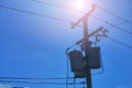Energy and technology: electrical post by the road with power line cables, transformers against bright blue sky Royalty Free Stock Photo