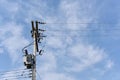 Energy and technology: electrical post by the road with power line cables, transformers against bright blue sky providing copy Royalty Free Stock Photo