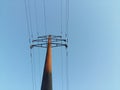 Energy and technology: electrical post by the road with power line cables, transformers and phone lines against bright blue sky Royalty Free Stock Photo