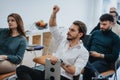 Engaged audience at a casual business seminar. Young, male employee raising hand to ask question during training at