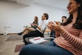 Engaged audience in a casual seminar environment, clapping hands appreciatively after a presentation. The group shows