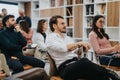 Engaged audience sits in a modern office workshop, with a young man in the foreground listening intently to a speaker.