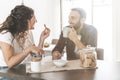 Engaged couple having breakfast together in their new home - young couple talking while eating and drinking in the kitchen - Royalty Free Stock Photo