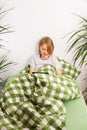 Engaged with his tablet, a young boy sits on the bed, exploring the internet in a relaxed manner Royalty Free Stock Photo