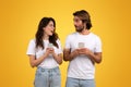 Engaged couple holding smartphones, the woman looking surprised and speaking to the man Royalty Free Stock Photo