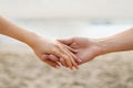Engagement concept. Young couple holding hands, man proposing to his girlfriend, walking on coastline, closeup Royalty Free Stock Photo