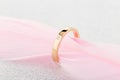 Engagement gold ring with one diamond on pink feather