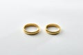 Engagement gold rings side by side on white textured base