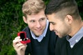 Engagement proposal betwen two gay men as one man proposes with an engagement ring in red box Royalty Free Stock Photo