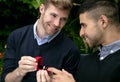 Engagement proposal betwen two gay men as one man proposes with an engagement ring in red box Royalty Free Stock Photo