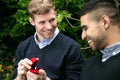 Engagement proposal betwen two gay men as one man proposes with an engagement ring in red box Royalty Free Stock Photo