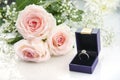 Engagement ring in a box and pink roses on white background Royalty Free Stock Photo