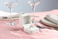 Engagement ring in box and tableware on pink tablecloth, closeup. Romantic dinner Royalty Free Stock Photo