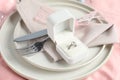 Engagement ring in box and tableware on pink tablecloth, closeup. Romantic dinner Royalty Free Stock Photo