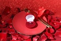Engagement ring in box, tableware and rose petals on red glitter background, closeup. Table setting for romantic dinner Royalty Free Stock Photo