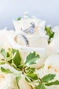 Engagement ring paired with wedding bands, resting on a bouquet of white roses Royalty Free Stock Photo